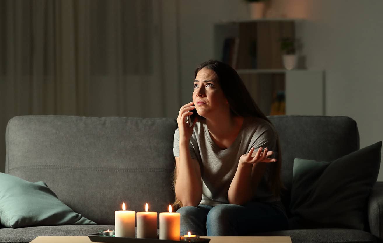 Concerned woman during power outage with candles | RC Solar & Roofing backup solutions